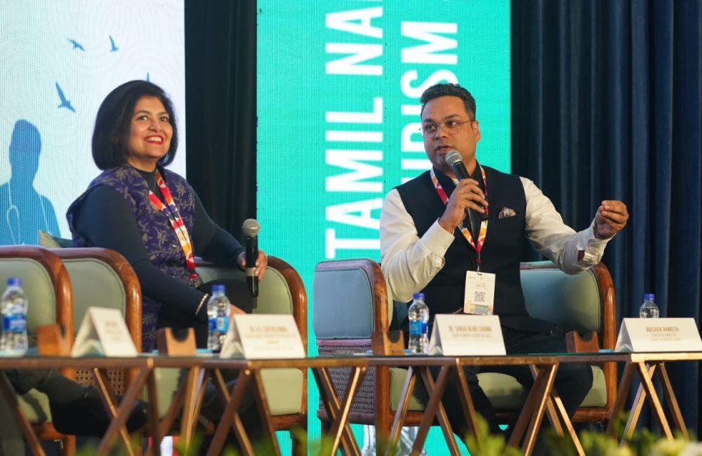Panelists discuss everyday wellness in travel at a Tamil Nadu Tourism event; a Kairali Ayurvedic Group representative speaks.