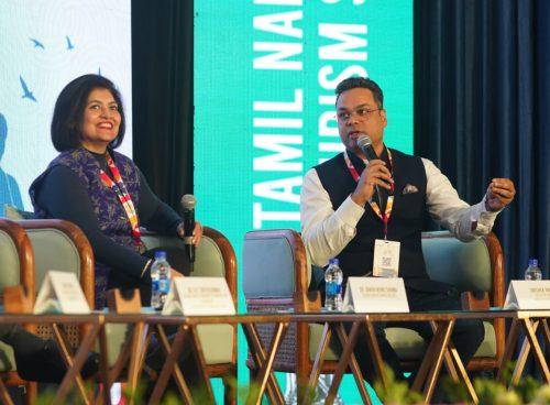 Panelists discuss everyday wellness in travel at a Tamil Nadu Tourism event; a Kairali Ayurvedic Group representative speaks.