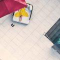 Aerial view of a guest relaxing on a sun lounger under a red umbrella beside a patterned pool at Villa Raag.