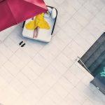 Aerial view of a guest relaxing on a sun lounger under a red umbrella beside a patterned pool at Villa Raag.