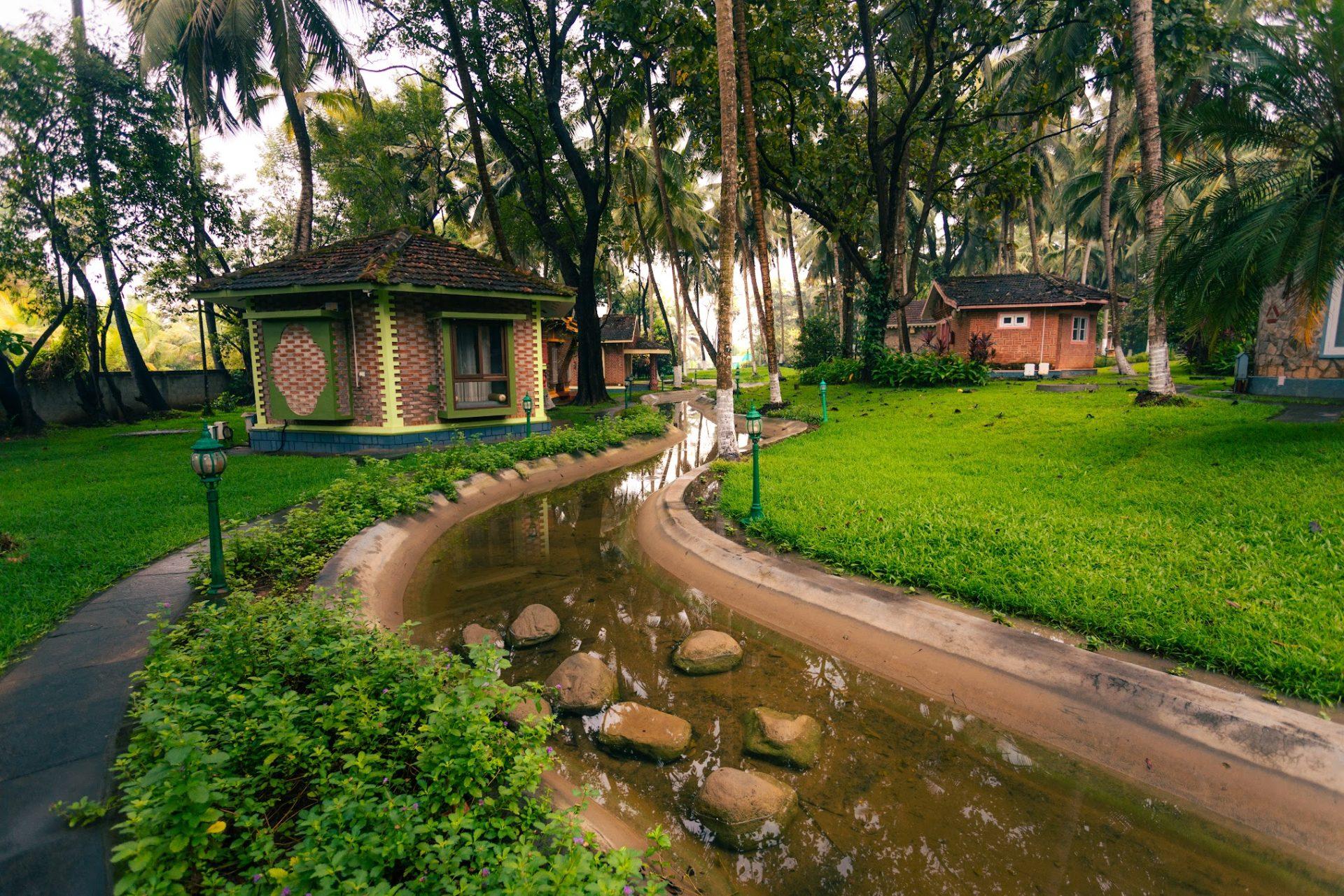 Brick cottage cottages with green trim along a winding water channel surrounded by lush palm trees and manicured lawns