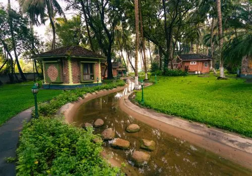 Brick cottage cottages with green trim along a winding water channel surrounded by lush palm trees and manicured lawns