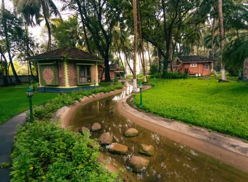 Brick cottage cottages with green trim along a winding water channel surrounded by lush palm trees and manicured lawns