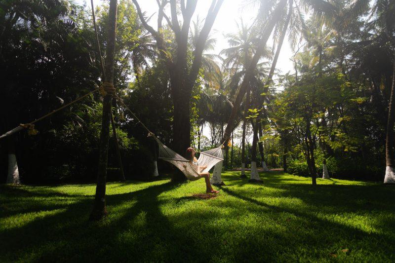 Woman relaxing on a hammock amidst lush greenery at Kairali Ayurvedic Healing Village, a serene Kerala Ayurveda destination for holistic wellness and rejuvenation.