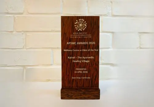 Wooden award plaque from the Asia Pacific Spa & Wellness Coalition, engraved with "APSWC Awards 2026 – Wellness Centre or Clinic of the Year – Kairali – The Ayurvedic Healing Village – Presented 24 April 2026, Siem Reap, Cambodia.