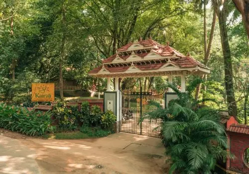 Entrance gate of Kairali The Ayurvedic Healing Village surrounded by lush green trees in Kerala