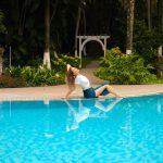 Woman relaxing beside a swimming pool surrounded by tropical greenery at Kairali – The Ayurvedic Healing Village in Kerala, India.
