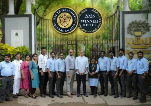 Kairali Ayurvedic Health Resort team posing in front of the resort's entrance gate, with overlaid Haute Grandeur Global Awards 2026 Winner Hotel badges.