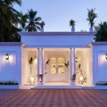 White colonial-style villa entrance in Agonda Beach, Goa, with columned portico, warm lighting, and palm trees at dusk