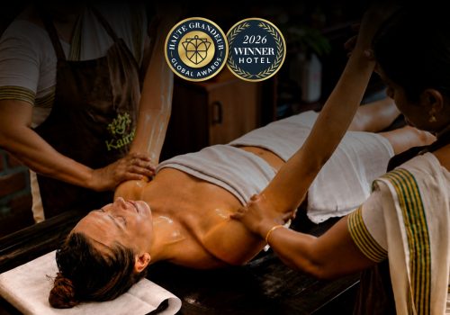 Kairali Ayurvedic therapists performing a traditional Ayurvedic oil therapy at Kairali – The Ayurvedic Healing Village, recognised at the 2026 Haute Grandeur Global Excellence Awards.