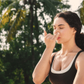 Woman practicing alternate nostril breathing as part of a somatic morning routine surrounded by palm trees