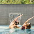 Yoga pose for core strength – man and woman practicing side stretch pose in a resort pool