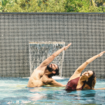 Yoga pose for core strength – man and woman practicing side stretch pose in a resort pool