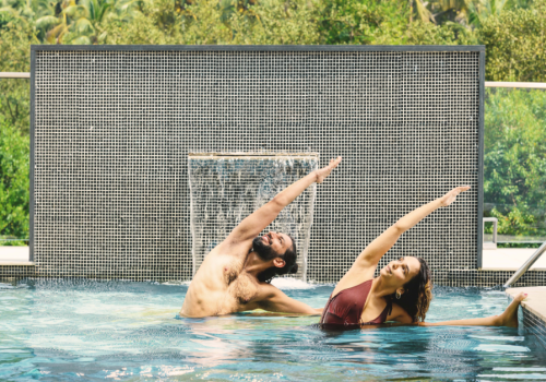 Yoga pose for core strength – man and woman practicing side stretch pose in a resort pool