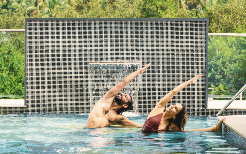 Yoga pose for core strength – man and woman practicing side stretch pose in a resort pool
