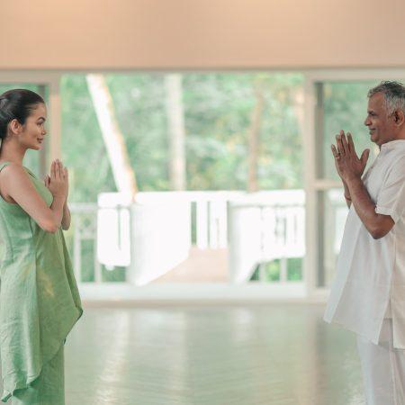 Wellness expert greets guest with namaste before guiding her on common yoga mistakes beginners make