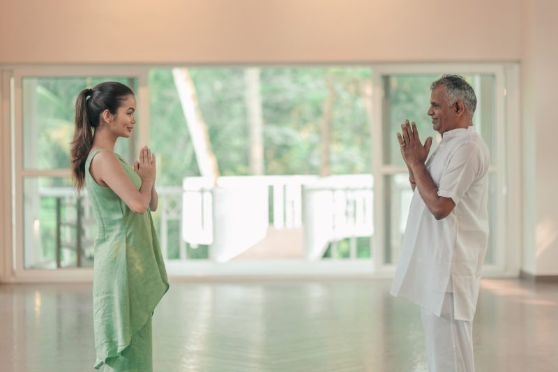 Wellness expert greets guest with namaste before guiding her on common yoga mistakes beginners make