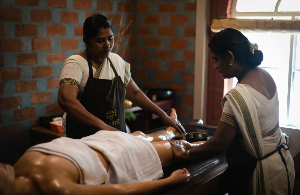 Ayurvedic oil therapy being performed by two therapists at Kairali – The Ayurvedic Healing Village in Kerala.