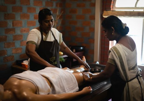 Ayurvedic oil therapy being performed by two therapists at Kairali – The Ayurvedic Healing Village in Kerala.
