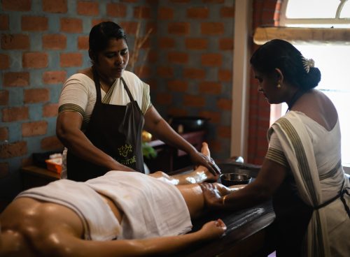 Ayurvedic oil therapy being performed by two therapists at Kairali – The Ayurvedic Healing Village in Kerala.