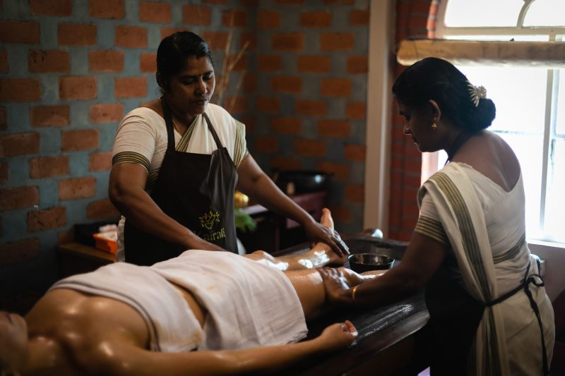 Ayurvedic oil therapy being performed by two therapists at Kairali – The Ayurvedic Healing Village in Kerala.