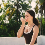 Woman practising alternate-nostril breathing outdoors at a tropical wellness retreat.