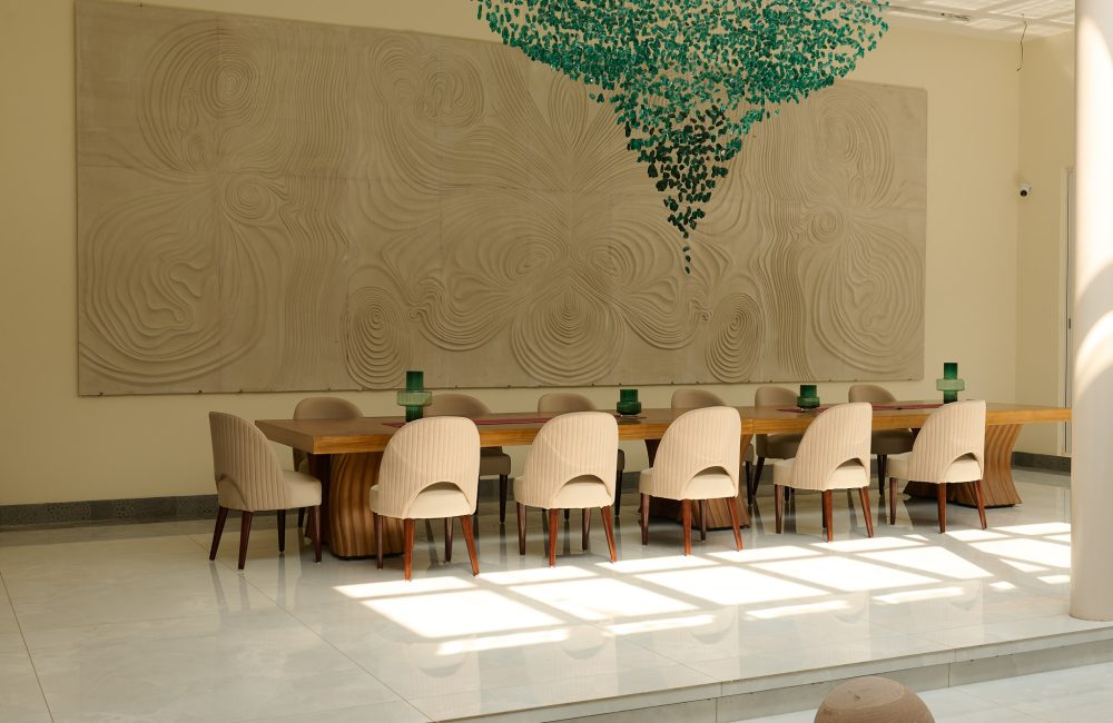 Elegant dining area at Villa Raag, a yoga retreat in Goa, with sculptural wall art and contemporary interiors.