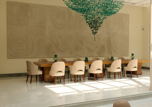 Elegant dining area at Villa Raag, a yoga retreat in Goa, with sculptural wall art and contemporary interiors.