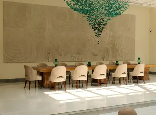 Elegant dining area at Villa Raag, a yoga retreat in Goa, with sculptural wall art and contemporary interiors.