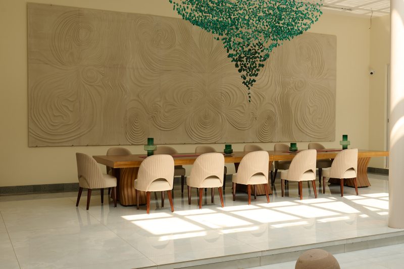 Elegant dining area at Villa Raag, a yoga retreat in Goa, with sculptural wall art and contemporary interiors.