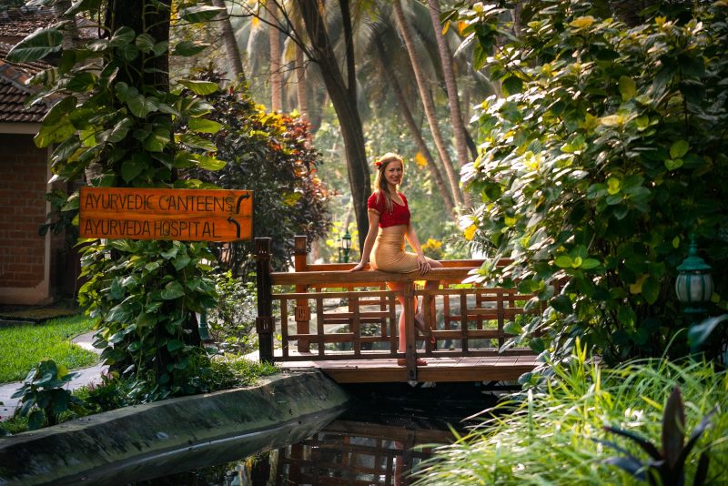 Brahma Muhurta benefits in Ayurveda: A woman enjoying the peaceful early morning surroundings of a lush Ayurvedic wellness retreat in Kerala.