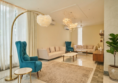 Elegant lounge interior with teal armchairs, cream sofas, modern lighting and comfortable seating for a workation in Agonda.