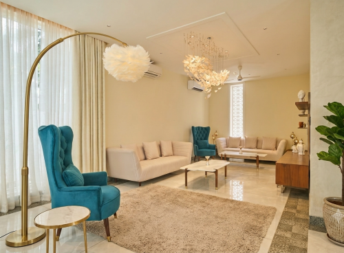 Elegant lounge interior with teal armchairs, cream sofas, modern lighting and comfortable seating for a workation in Agonda.