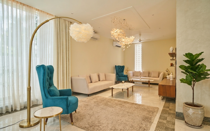 Elegant lounge interior with teal armchairs, cream sofas, modern lighting and comfortable seating for a workation in Agonda.