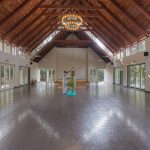 Yoga to lower cortisol: A guided yoga session at Kairali Ayurvedic Healing Village in Palakkad, Kerala, inside a spacious, naturally lit yoga hall.